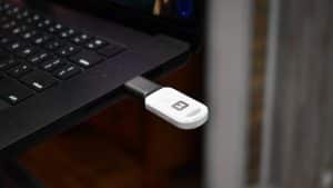 Close-up of a black and white USB device plugged into a black laptop.